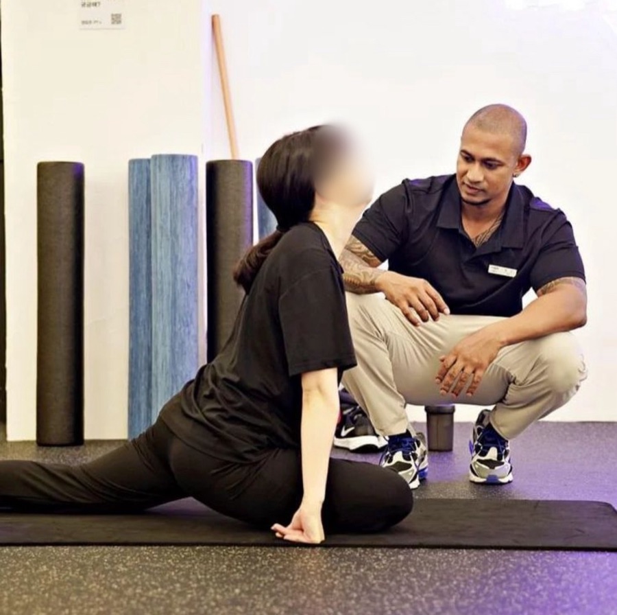 Coach Vinzy guiding a client through a hip stretch